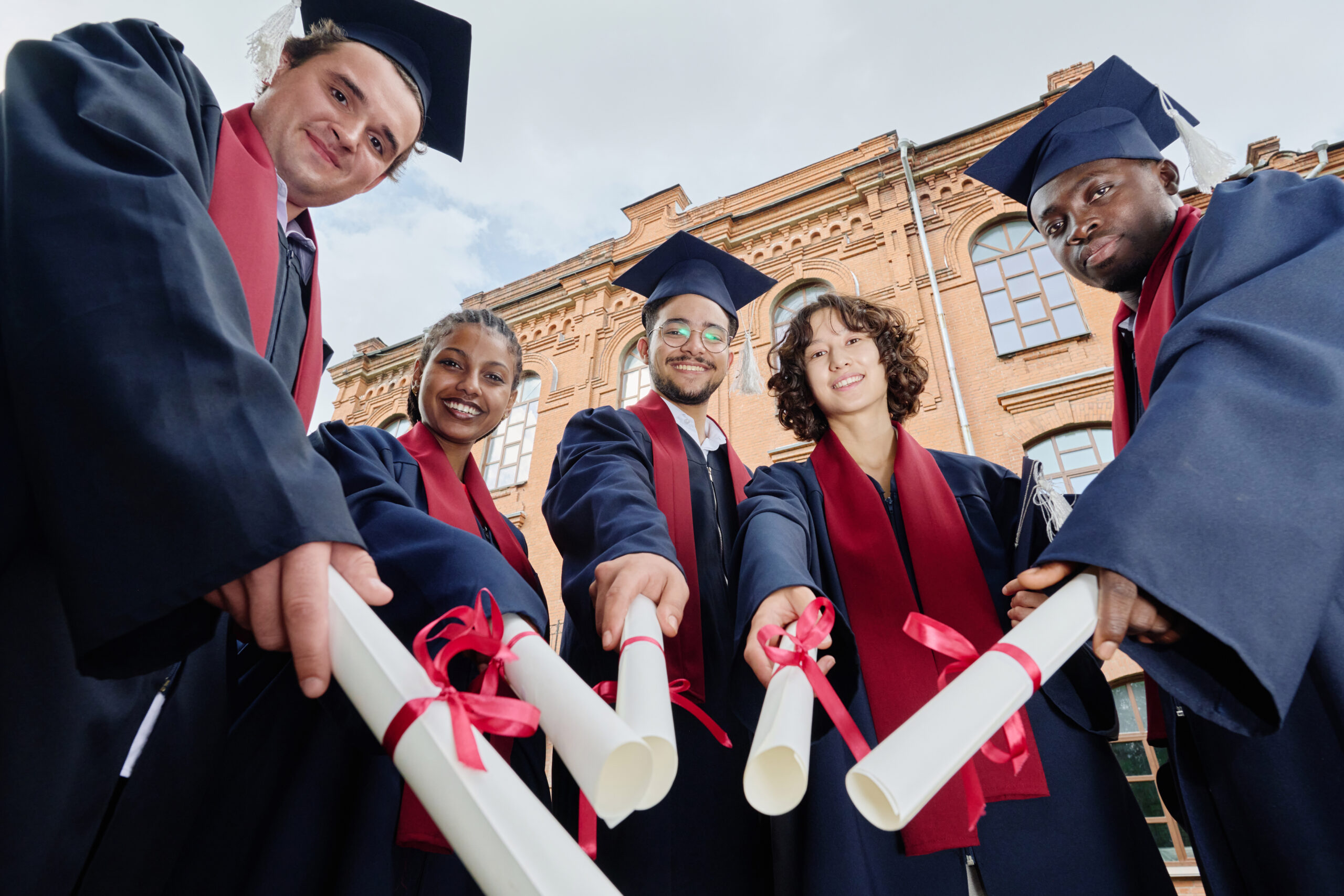 Graduated students with diplomas standing outdoors