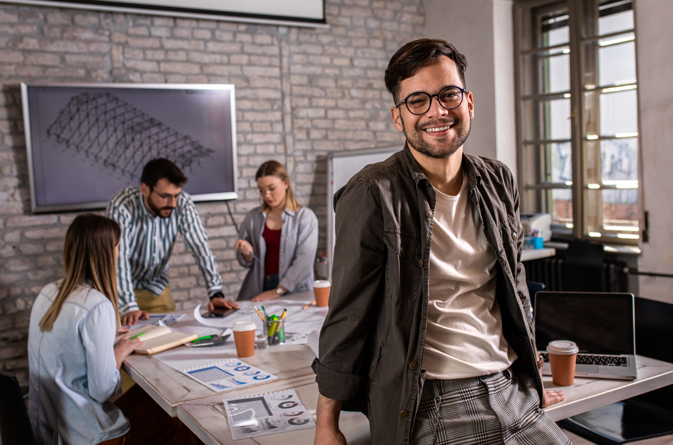 Portrait of confident young male leader standing in office.